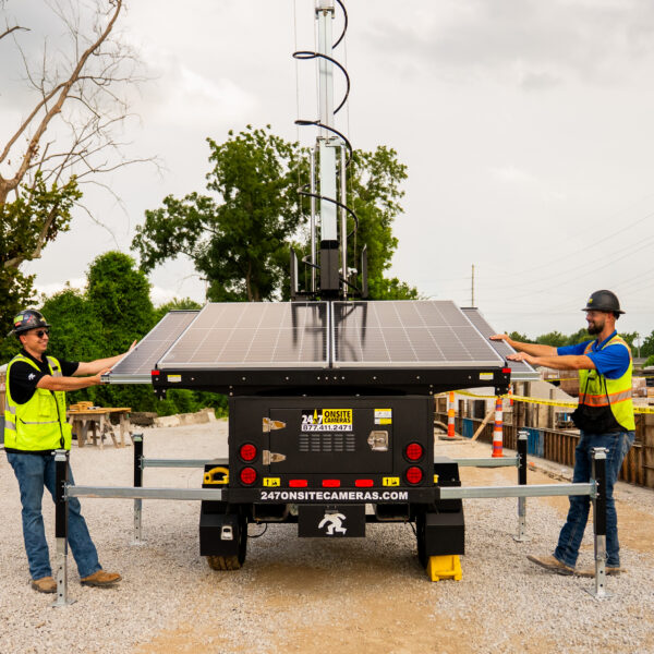 Workers in safety gear adjust solar panels onsite.
