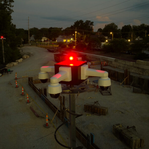Mounted camera with red lights hovers over dusk construction site.