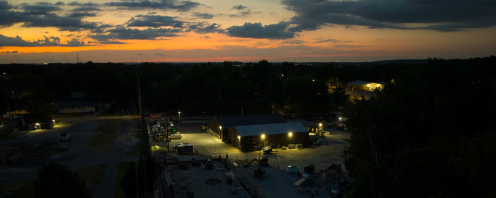 Industrial building at dusk with trees and sunset sky.