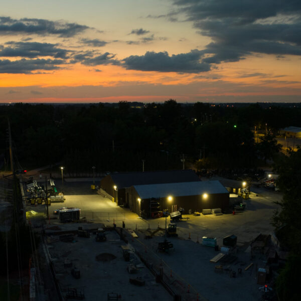 Industrial building at dusk with trees and sunset sky.