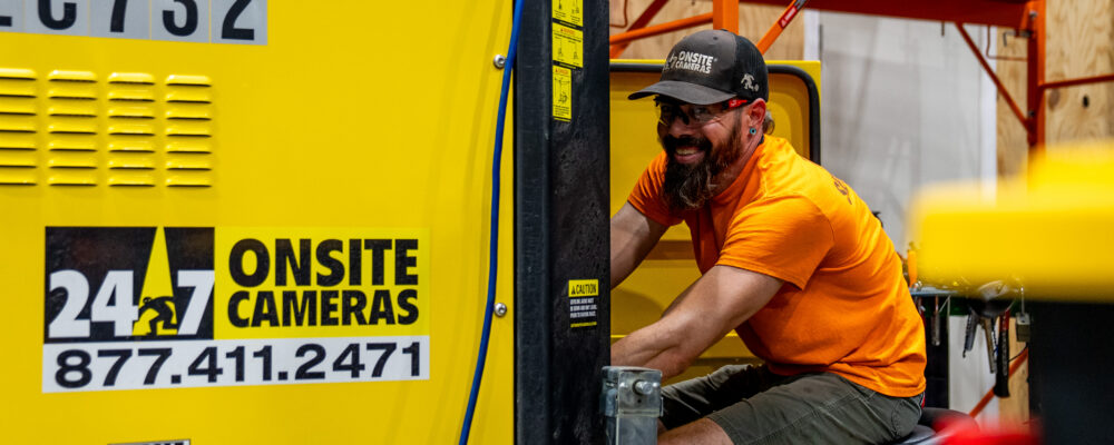 Man in orange shirt works on 24/7 Onsite Cameras equipment.