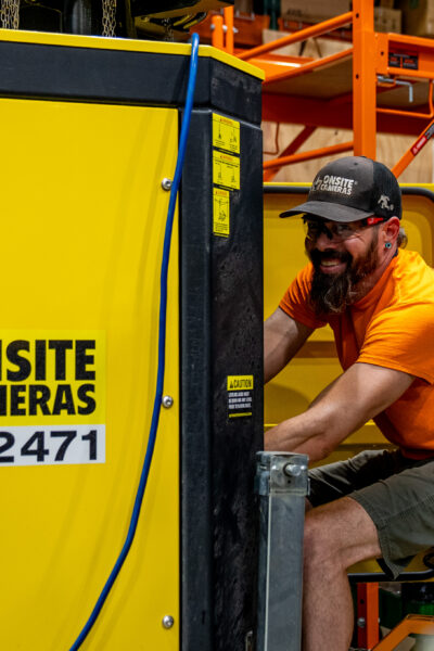 Man in orange shirt works on 24/7 Onsite Cameras equipment.