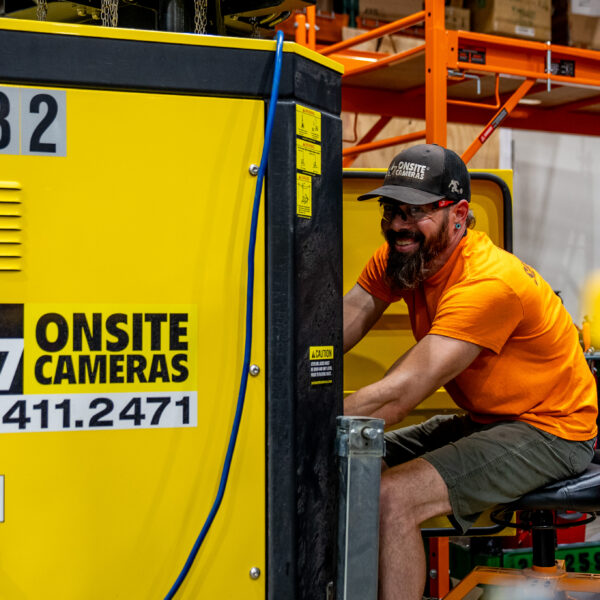 Man in orange shirt works on 24/7 Onsite Cameras equipment.