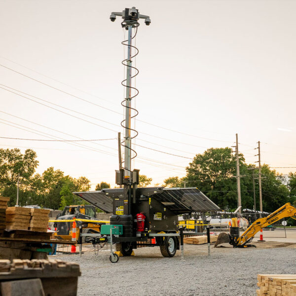 Mobile security camera tower with solar panels at construction site.