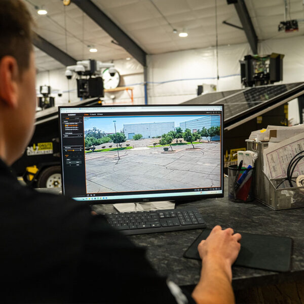Person at desk watching parking lot footage on monitor.