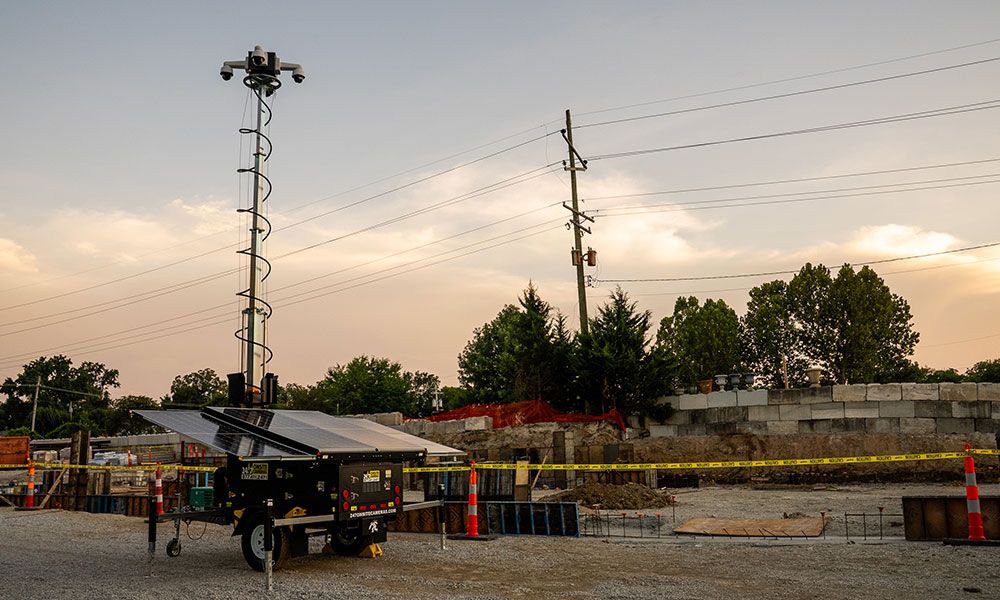 Surveillance camera tower with solar panels at construction site.