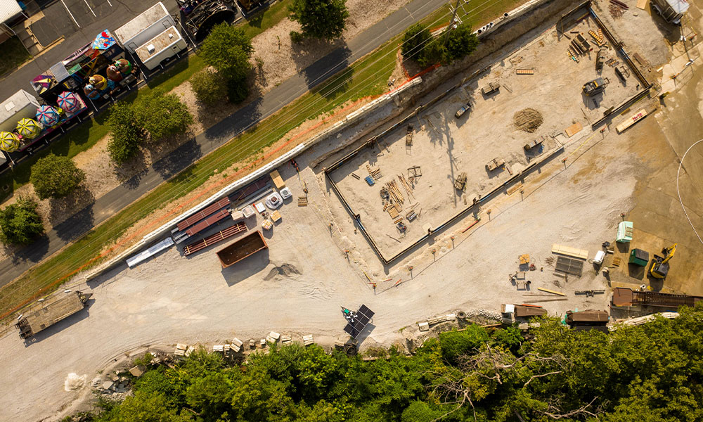 Aerial shot of site with vehicles, materials, and foundation.