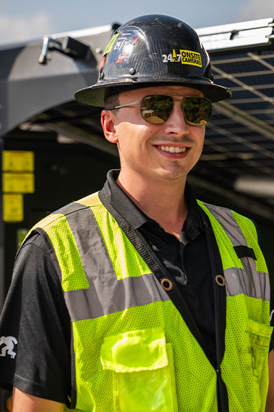 Smiling man in safety gear stands by construction equipment.