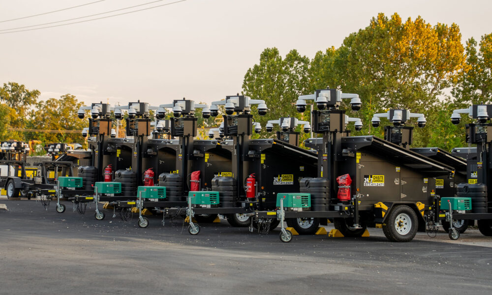 Green-based light towers in a row on outdoor lot.