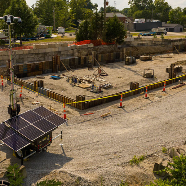 Construction site foundation, caution tape, cones, forms, solar panel security camera.
