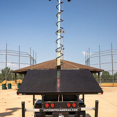 Surveillance unit with cameras and solar panels near sports field.