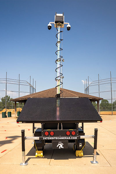 Surveillance unit with cameras and solar panels near sports field.